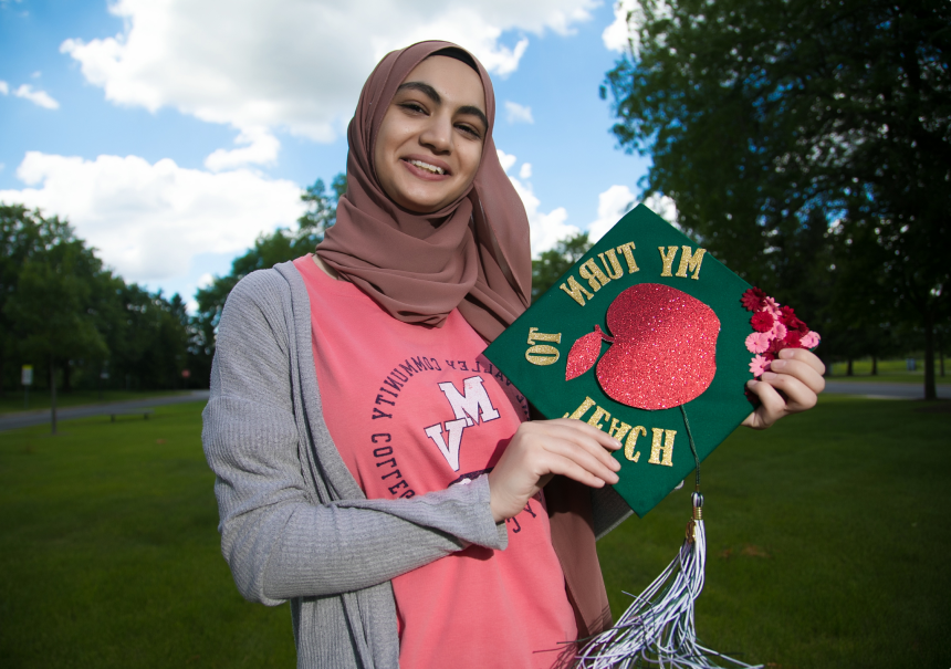 Rama Diab, current student at GSU, holding a graduation cap that says, ‘my turn to teach’