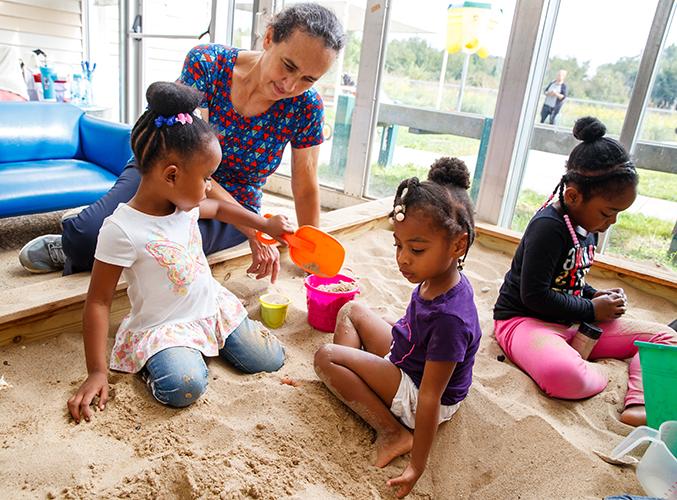 FDC staff member playing with children in sandbox